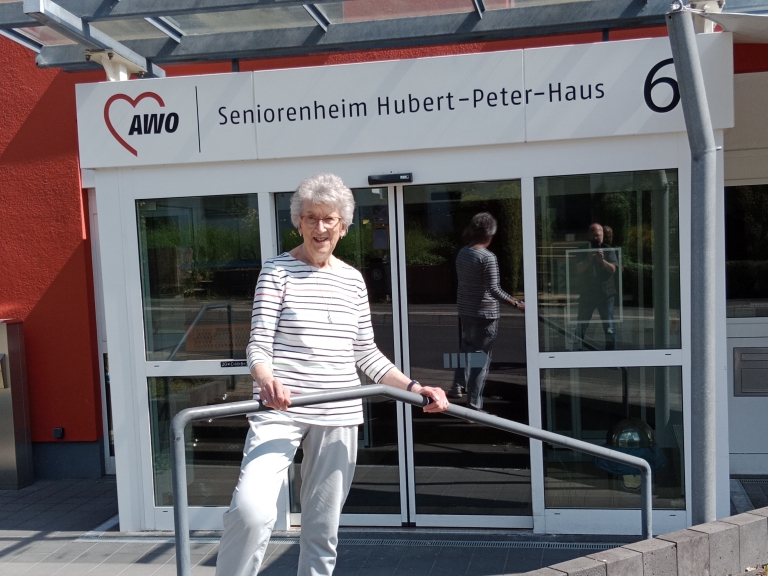 Frau Renate Schilling steht vor dem Seniorenheim Hubert-Peter-Haus