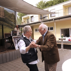 Zwei ältere Menschen tanzen draußen miteinander