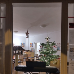 Klavier im Fenster, dahinter ein schön-geschmückter Tannenbaum